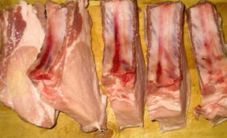 Cum să gătești delicios coaste de porc pe grătar într-o marinadă? Pregătiți carnea și tăiați-o de-a lungul coastelor.