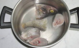 Skär fisken i flera bitar. Det är tillrådligt att inte lägga huvudet till buljongen. Denna teknik kommer att göra soppan rikare och godare. Fyll pannan med 2 liter vatten. Vi överför de förberedda fiskbitarna till den.Det är mycket viktigt att vattnet bara täcker dem lätt, eftersom det klassiska receptet inte kräver att man använder en stor mängd vatten. Överför pannan till spisen och koka fisken i 15 minuter. 