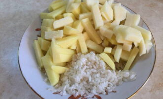 Rentar l'arròs i tallar les patates pelades a daus petits. Bullir el menjar en una cassola amb aigua.