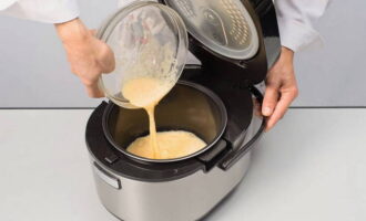 Haal de pan uit de multikoker en vet hem in met boter. Giet het melk-eimengsel en water erbij. 