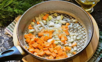Mentrestant, piqueu les cebes i les pastanagues pelades. Escalfeu oli vegetal en una paella i fregiu les verdures fins que estiguin toves, sense deixar de remenar perquè no es cremi res.
