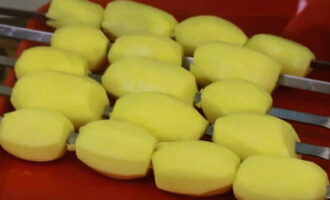 Enfileu les patates senceres a una broqueta. Quan hàgiu acabat amb totes les broquetes, assequeu-ho tot amb un tovalló de paper o una tovallola. Fem diversos talls a banda i banda de les patates perquè després sigui més fàcil que la salsa s'absorbeixi al plat. Arrebossem cada patata amb salsa.