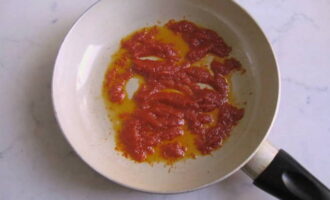 Adauga pasta de rosii intr-o tigaie incinsa cu ulei de floarea soarelui pana se prajeste usor.