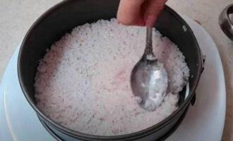 Đặt một tấm nori tròn lên một đĩa lớn và đặt một đĩa nướng. Chúng tôi bắt đầu bày ra một nửa phần cơm của mình. Cố gắng phân bố đều trên toàn bộ diện tích của nori và nén chặt. 