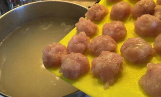 Submergeix les mandonguilles crues en una paella amb aigua. Afegiu espècies al gust.