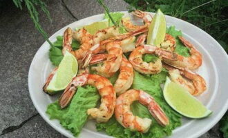 Leg de afgewerkte langoustines op een serveerbord met slablaadjes. Versier het gerecht met partjes limoen en serveer. Eet smakelijk!