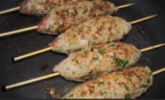 Poseu la paella al foc i escalfeu-la. Lubriqueu la seva superfície amb oli de gira-sol. És desitjable que sigui inodor. Col·loqueu els futurs kebabs de lula a la paella. Comencem a fregir-los. Ho fem a foc fort. Donar la volta constantment a les costelles amb una broqueta, fregint-les per tots els costats durant 1-2 minuts. Com que fregim les costelles a foc fort, a la seva superfície es forma una crosta daurada. És ella qui té tot el suc de lula kebab dins. Per tant, el plat resulta increïblement sucós.