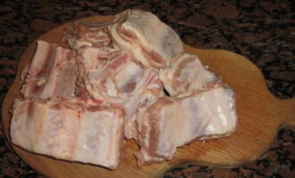 Paano masarap magluto ng mga buto-buto ng baboy na may patatas sa oven? Hugasan namin ang mga buto-buto sa ilalim ng tubig na tumatakbo at pinutol ang mga ito kasama ang mga buto sa mga bahagi.