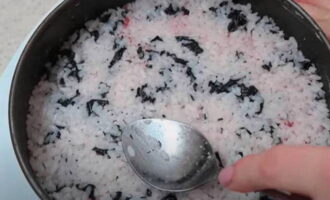 Chúng ta cần trộn nửa số gạo còn lại với những miếng nori cắt sẵn. Rải hỗn hợp thu được lên cá. Dùng thìa san phẳng lớp và dùng nó để nén chặt. 