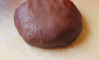 După aceasta, îndepărtați masa de pe foc, adăugați făină, smântână, cacao și praf de copt, amestecați. Aluatul trebuie să fie moale și flexibil. Înveliți-l în folie alimentară și puneți-l la frigider pentru o oră.