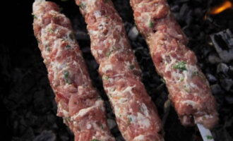 Inilalagay namin ang tinadtad na karne sa mga skewer upang ang hugis nito ay kahawig ng isang mahabang pahaba na cutlet. Ilagay ang lula kebab sa grill at iprito sa lahat ng panig, pana-panahong iikot ang mga skewer. 