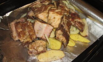 Takpan ang mga patatas at sibuyas gamit ang mga buto-buto at ibuhos ang toyo sa kanila.