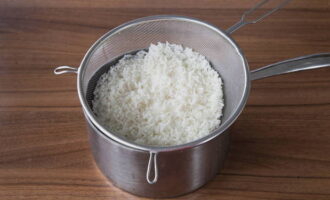 Cách nấu món bắp cải cuộn sốt kem chua cà chua trong lò nướng? Đầu tiên, chúng ta hãy nấu cơm, thứ cần thiết để làm món bắp cải cuộn. Cho ngũ cốc vào nước sôi, thêm muối và đun sôi lại.Sau đó giảm nhiệt xuống thấp và nấu trong mười phút. Đặt gạo thành phẩm vào một cái rây, chắt hết nước và để nguội ở nhiệt độ phòng.