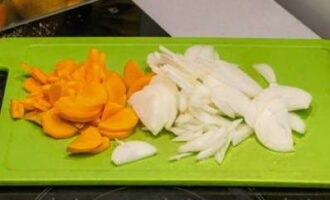 Hoe maak je gepureerde courgettesoep volgens het klassieke recept? Schil de uien en wortels. Snijd vervolgens de groenten in kleine stukjes.