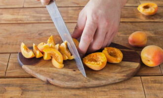 Làm thế nào để nướng món bánh charlotte thơm ngon với quả mơ trong lò? Chúng ta rửa sạch quả mơ, lau khô và cắt chúng thành hai nửa rồi cắt thành từng lát.