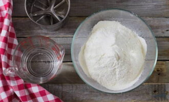 Hoe maak je thuis dumplings met kersen klaar volgens het klassieke recept? Zeef de bloem in een kom en voeg zout toe.