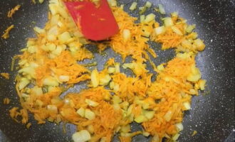 Se rade morcovii decojiti pe razatoarea grosiera si se toaca marunt rosiile.Tăiați a doua ceapă în cuburi și prăjiți cu ulei vegetal într-o tigaie încălzită. Când ceapa devine translucidă și începe să devină aurie, adăugați restul de legume tocate.