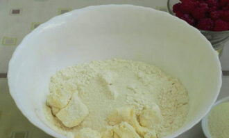 Napakadaling maghurno ng raspberry pie sa oven. Salain ang harina sa isang mangkok, magdagdag ng asukal at mantikilya, ihalo ang mga sangkap gamit ang iyong mga kamay.
