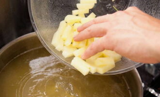 We halen het kippenvlees uit de pan, halen de botten eruit en sturen het terug. Was de aardappelen, schil ze, snijd ze in blokjes of partjes en doe ze op het vuur in de pan. Op dit moment maken we dumplings. 