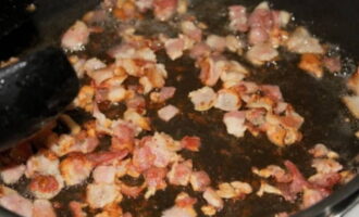 Poseu la cansalada a la paella. Fregiu-lo durant 5-7 minuts. El senyal de preparació serà l'escorça daurada que es forma a la superfície de la cansalada. Després d'això, hem de col·locar els trossos sobre una tovallola de paper per eliminar l'excés de greix de la carn. La paella no s'ha d'enviar immediatament a l'aigüera, ja que encara la necessitarem durant el procés de cocció.    