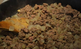 Tăiem ceapa în forme arbitrare: o puteți toca sau o puteți tăia în felii alungite. Luați o tigaie, umeziți-o cu ulei vegetal și puneți peste ea ceapa deja tocată. Se prăjește câteva minute la foc mediu. Adăugați carnea tocată, sare și condimente la ceapă. Se amestecă bine și se prăjește timp de 5 minute.