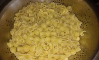 Doe de gekookte pasta in een vergiet, laat het vocht uitlekken en spoel de pasta af onder stromend water. Het is niet nodig om de pasta af te spoelen, dit is optioneel.