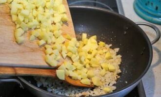 Snijd de ui fijn en bak deze goudbruin in plantaardige olie. Vervolgens leggen we de aardappelen neer.