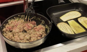 Hetta upp olivolja i en stekpanna och fräs lök och vitlök i den tills de blir genomskinliga. Tillsätt sedan köttfärsen, blanda och koka i 10 minuter. Stek aubergineskivorna på båda sidor i en separat stekpanna tills de är gyllenbruna och överför till en pappershandduk för att absorbera överflödigt fett. Hetta upp olivolja i en stekpanna och fräs lök och vitlök i den tills de blir genomskinliga. Tillsätt sedan köttfärsen, blanda och koka i 10 minuter.Stek aubergineskivorna på båda sidor i en separat stekpanna tills de är gyllenbruna och överför till en pappershandduk för att absorbera överflödigt fett.