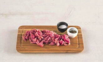 Per preparar stroganoff de vedella segons la recepta clàssica, rentar la carn de porc i tallar-la a tires petites. Espolvorear la carn amb sal i pebre, remenar i deixar 20 minuts.