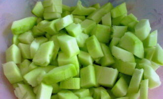 När vi steker lök och morötter distraheras vi av zucchini. Vi sköljer den nödvändiga mängden och torkar med en handduk. Putsa skalet och skär grönsaken i medelstora tärningar.