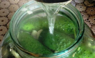Pune o cratiță cu apă pe arzător. Porniți aragazul și aduceți lichidul la fierbere. Turnați apă clocotită peste castraveții din borcane. Acoperiți recipientele cu capace și lăsați timp de 5 minute.