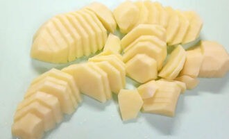 Banlawan ang mga patatas sa ilalim ng tubig na tumatakbo, alisan ng balat, gupitin sa kalahati at gupitin sa kalahating singsing na humigit-kumulang sa parehong kapal ng karne. Hindi na kailangang i-cut ang mga patatas sa masyadong makapal na piraso upang sila ay mahusay na inihurnong at ang karne ay walang oras upang matuyo sa oras na ito.