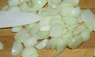 Balatan ang sibuyas at gupitin muli sa kalahating singsing.