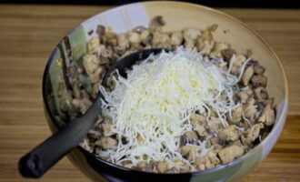 Voeg de rest van de geraspte kaas toe aan de kip en champignons.