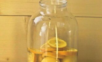 In een pot van 3 liter, die eerst moet worden gesteriliseerd, doe je abrikozen en plakjes sinaasappel en giet je kokend water over het fruit. 