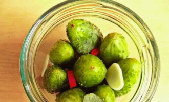 A continuació, envaseu els cogombres amb força i afegiu-hi una mica més de pebre i all per sobre.