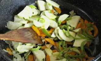 Pentru a tocana tocana, luați o tigaie adâncă. Încinge ulei vegetal în el și prăjește ceapa și morcovii tăiați la foc mare. Apoi adăugați dovleceii tăiați felii și ardeiul dulce și prăjiți timp de 7 minute, amestecând din când în când cu o spatulă.