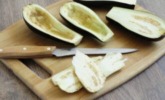 Com cuinar albergínies farcides al forn? Rentem les verdures amb aigua corrent. Quan la humitat s'assequi, talleu les albergínies en dues meitats al llarg de la fruita. Amb una cullera petita, traieu la polpa. Tritureu una petita quantitat de sal en vaixells. Talleu la polpa de l'albergínia a trossos petits.