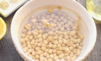 Hur gör man hummus hemma med ett klassiskt recept? Blötlägg kikärtorna i kallt vatten flera timmar i förväg. Du kan lämna den över natten. Produkten måste vara svullen för matlagning.