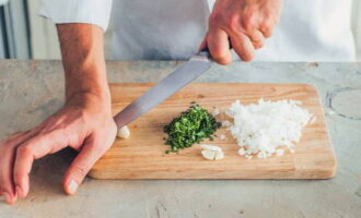 Paano gumawa ng risotto sa bahay? Pinong tumaga ang sibuyas at perehil gamit ang kutsilyo. Durugin ang sibuyas ng bawang.
