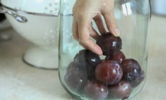 După ce fructele sunt pregătite și borcanele sunt sterilizate, aduceți apa la fiert și umpleți borcanele cu prune.