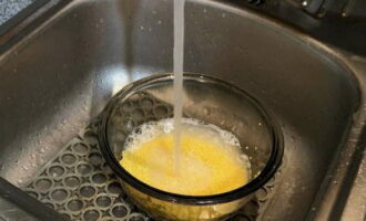 Spălăm de mai multe ori cerealele de mei sub jet de apă.