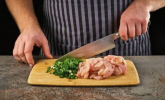 Apoi tăiem carnea în bucăți mici. Procedăm la fel și cu ceapa verde.