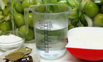 Doe de bereide groenten in gesteriliseerde potten en doe in elke pot knoflook, kruidnagel, zwarte peper en laurierblaadjes. 