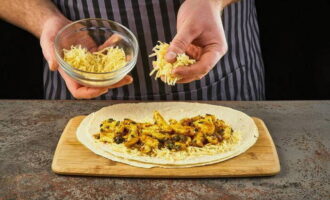 Întindeți brânză rasă și puiul prăjit pe jumătățile de tortilla.