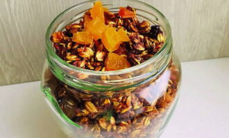 Adăugați caise uscate tăiate, prune uscate, stafide și merișoare, amestecați și transferați granola într-un recipient convenabil de depozitare.