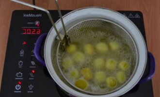 Turnați ulei vegetal într-o altă tigaie și puneți-l pe foc.Puneți o plasă de prăjire în ulei care fierbe, așezați o mică parte din piesele de prelucrat și prăjiți-le până când sunt fierte, amestecați periodic aluatul. Apoi, folosind o plasă, scoateți biluțele finite din ulei și așezați-le pe prosoape de hârtie. Faceți același lucru cu toate spațiile libere.