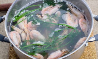 De îndată ce în bulion încep să apară primele bule, coborâți crustaceele nedecojite, aduceți din nou la fiert și opriți. Apoi acoperiți cu un capac și după două minute îndepărtați creveții folosind o lingură cu fantă.