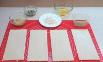 Com cuinar panets de pasta de full al forn? Prepareu els ingredients: mesura la quantitat necessària de fruits secs, xips de xocolata i puré de poma. Estireu lleugerament la massa de pasta de full amb un corró sobre una superfície enfarinada i talleu-la en 4 rectangles iguals.