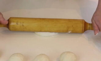 Hinahati muna namin ang bukol ng kuwarta sa mga lubid, na pagkatapos ay pinutol namin at nabuo sa mga bola. Ang bawat isa ay inilalabas namin gamit ang isang rolling pin sa isang hindi masyadong manipis na cake. Salamat dito, ang mga pie ay nagiging mas fluffier.